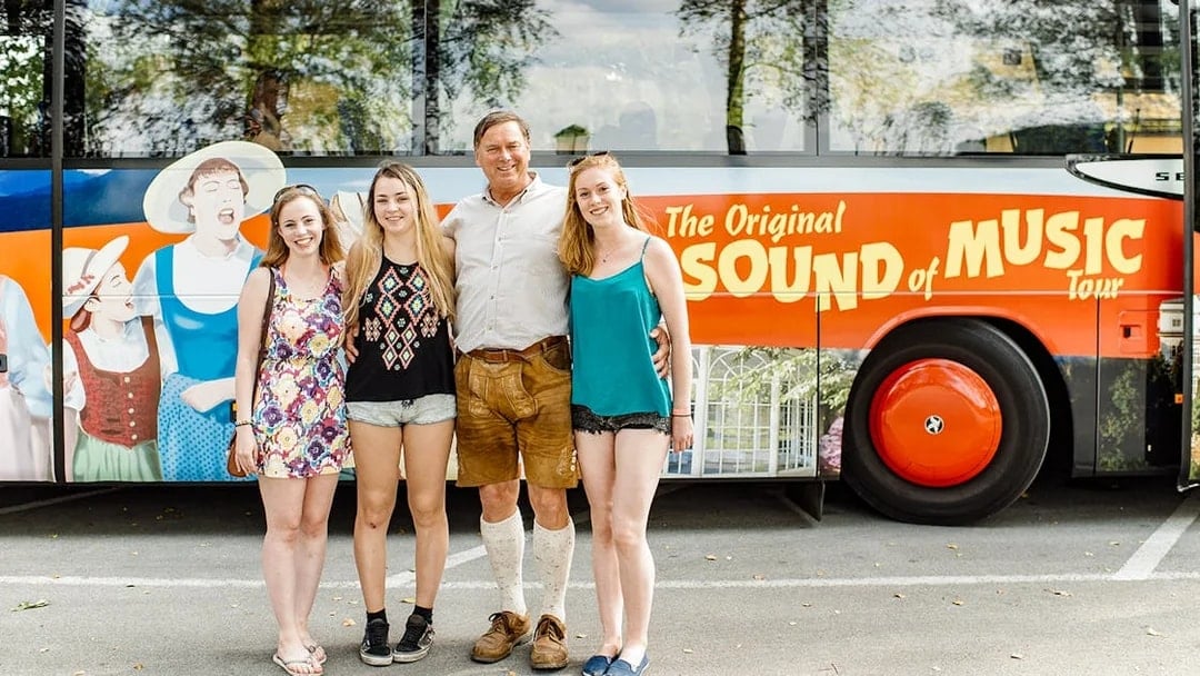 Tourists posing in front of the Original Sound of Music tour bus in Salzburg.