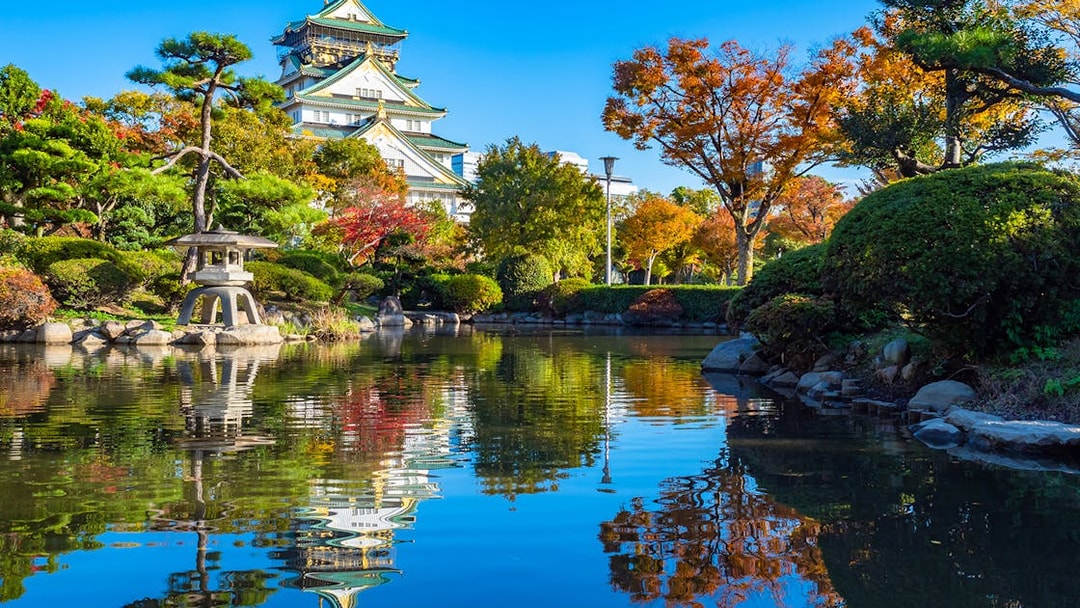 Osaka Castle gardens in spring with pond reflection, view from park, Japan.