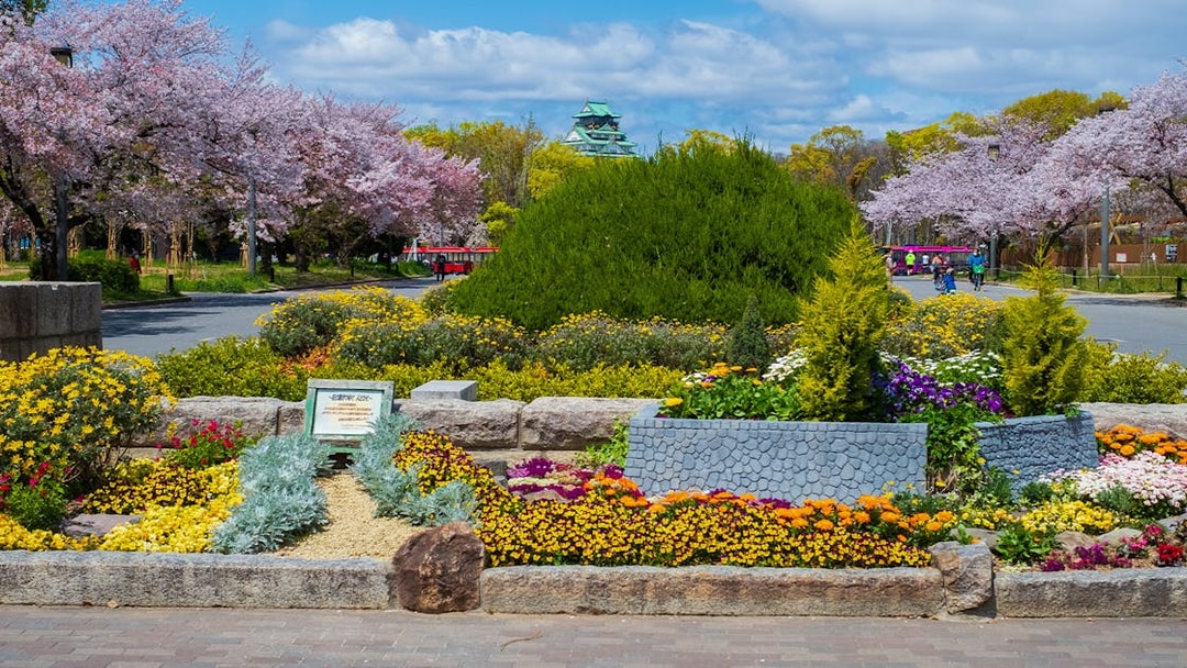 Osaka Castle with surrounding gardens and colorful flowers in bloom.