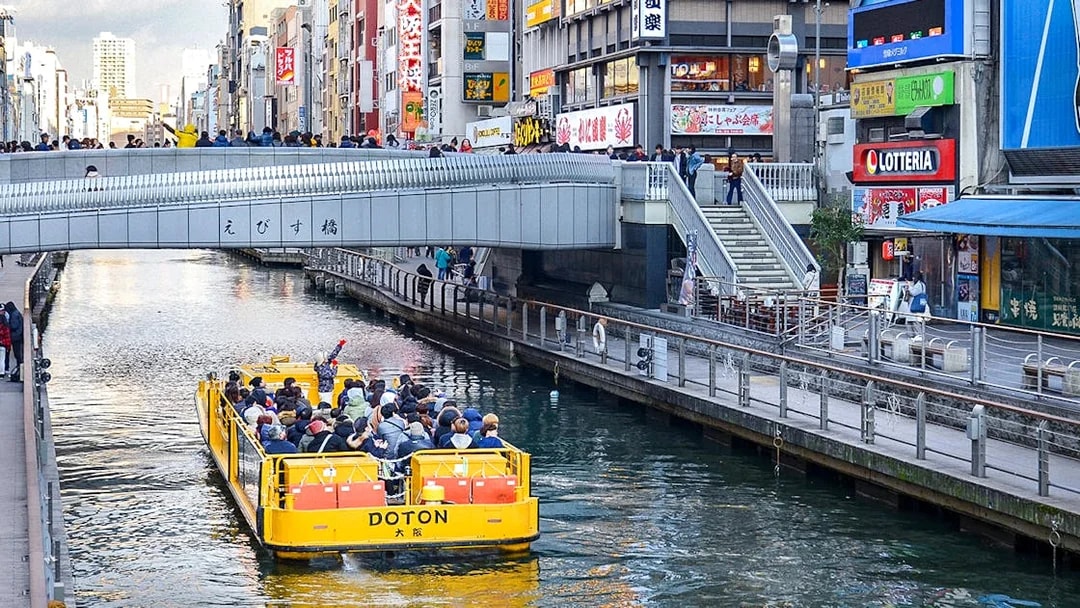 Tombori River Cruise boat passing under Ebisu Bridge in Osaka, Japan.