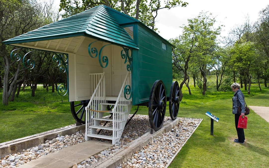 Historic carriage at Osborne House with visitor reading information sign.