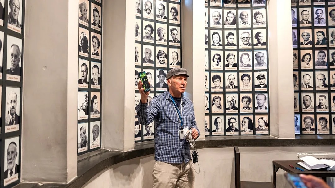 Guide explaining portraits of Oskar Schindler's factory employees during a tour.
