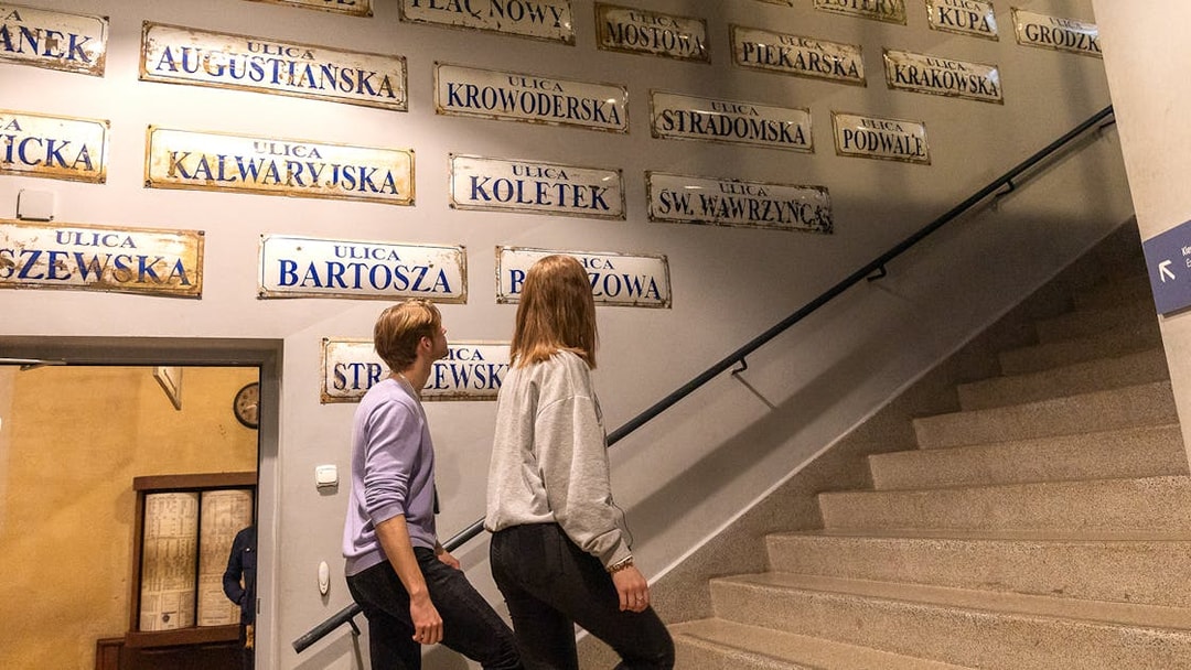 Couple exploring street signs inside Oskar Schindler's Factory, Krakow.