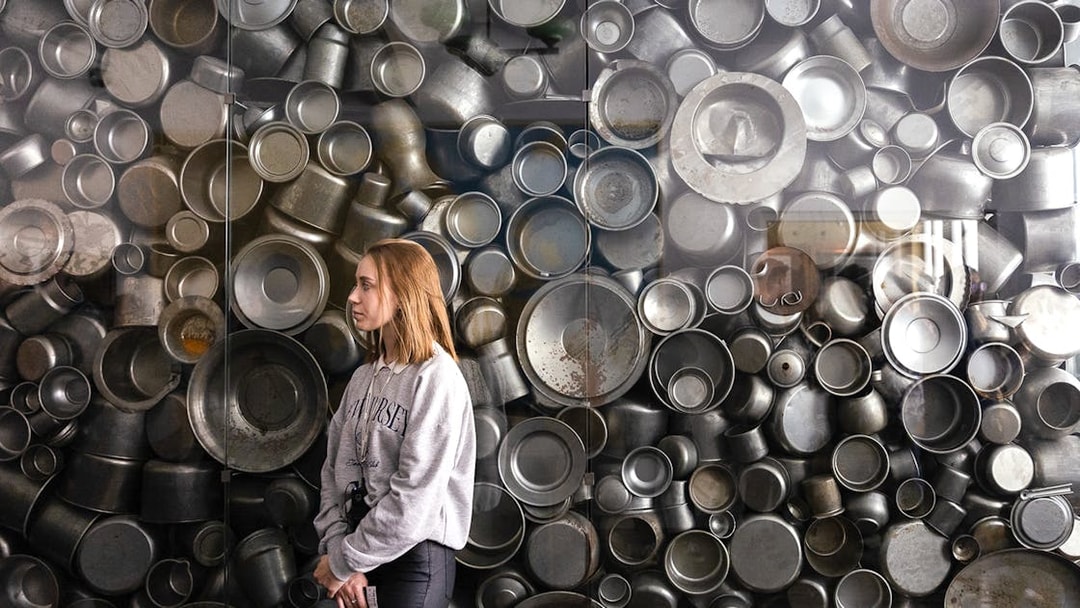 Enamelware display at Oskar Schindler's Factory, Krakow, with visitor observing.