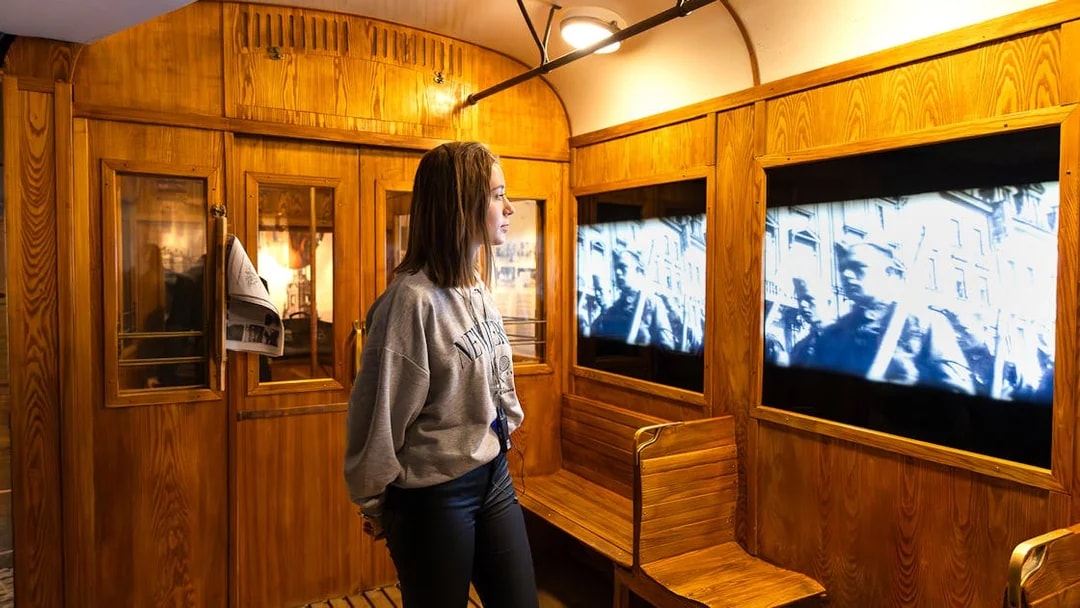 Train station exhibit inside Oskar Schindler's Factory with visitor watching historical footage.