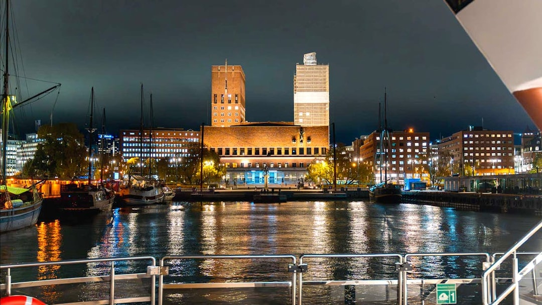 Oslo City Hall illuminated at night, viewed from a dinner cruise boat on the harbor.