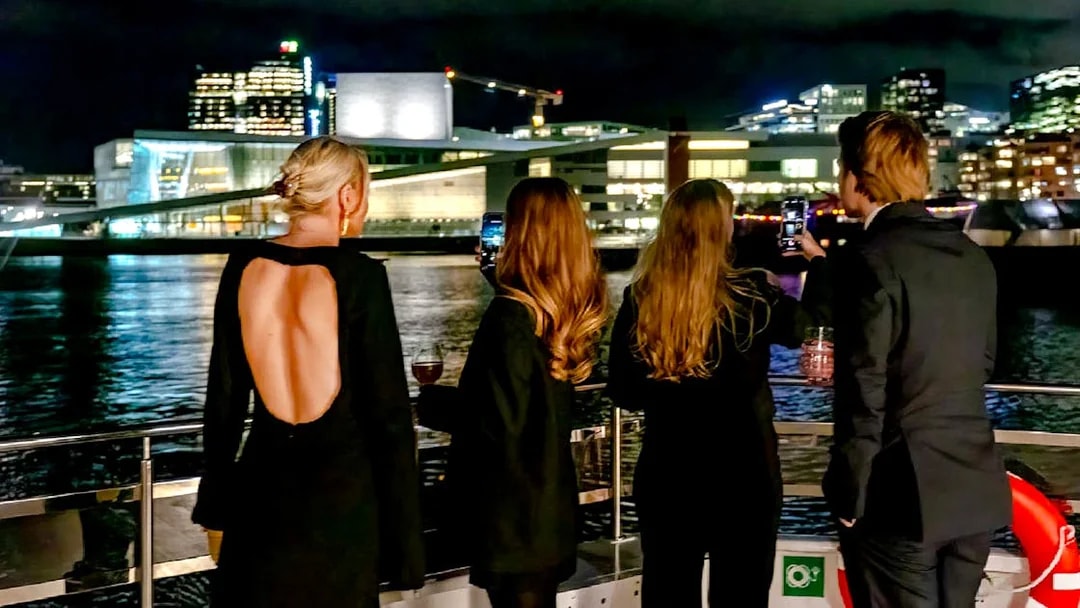 Guests enjoying Oslo skyline on a dinner cruise at night.