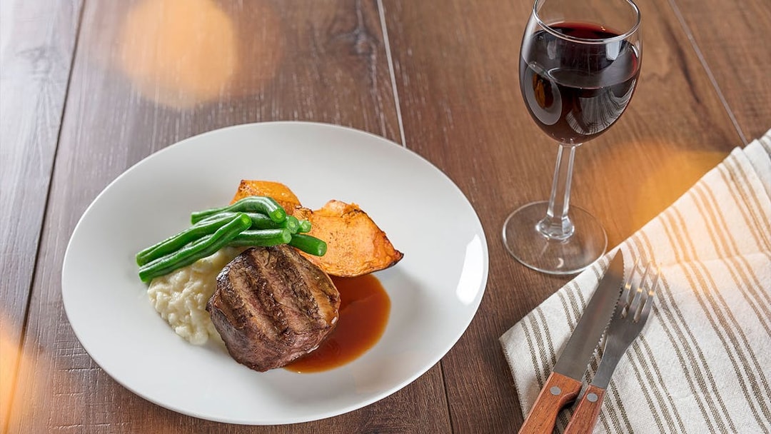 Steak dinner with green beans, sweet potato, and wine at Australian Outback Spectacular Heartland Show.