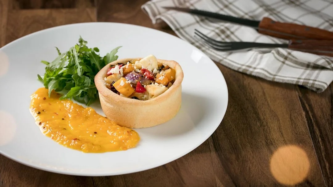 Australian Outback Spectacular dinner featuring a savory tart with salad and sauce.