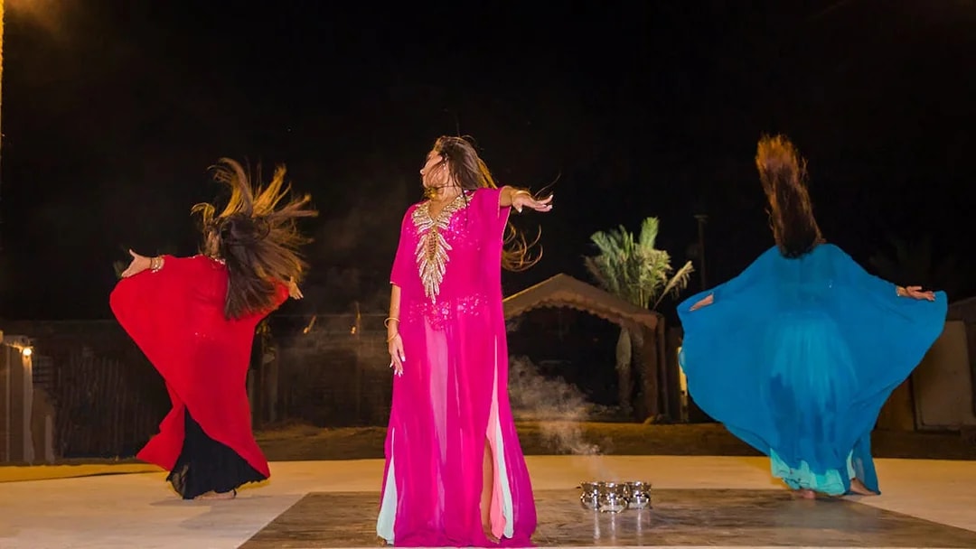 Dancers performing traditional Bedouin dance during desert safari night experience.