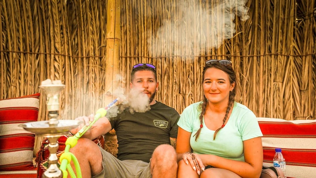 Couple enjoying shisha in a Bedouin tent during an overnight desert safari.