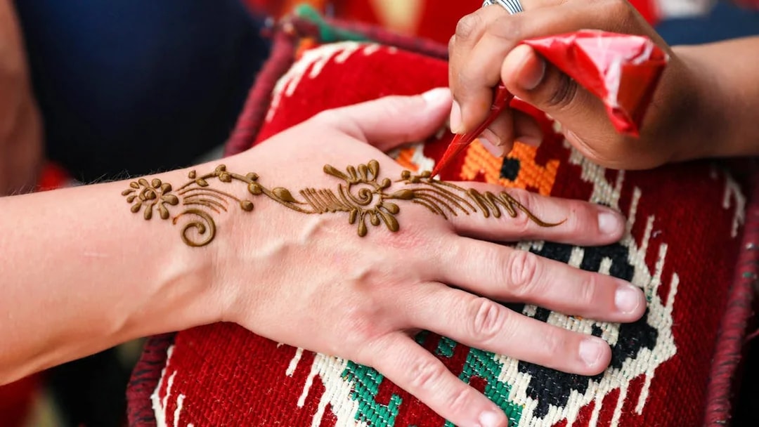 Henna design being applied on a hand during Bedouin desert safari.