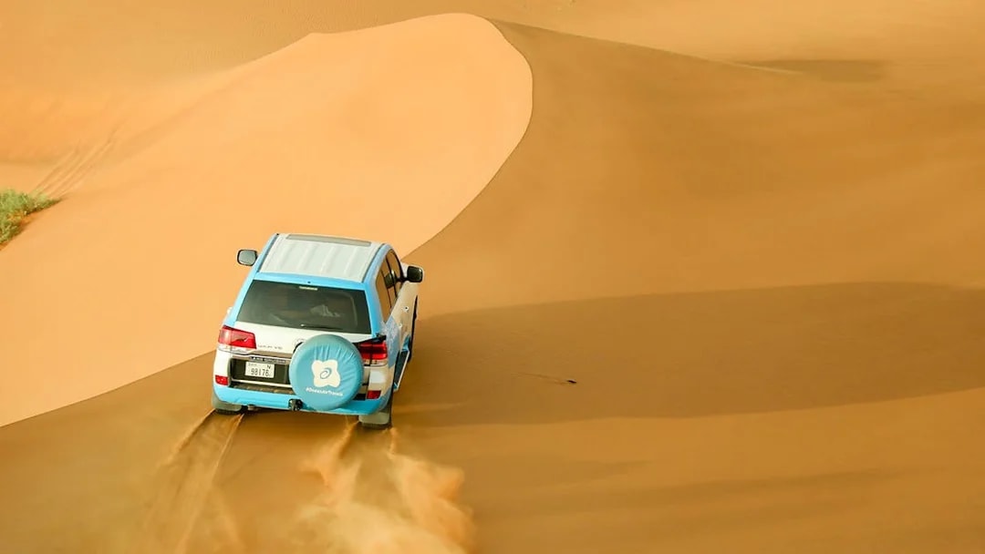 SUV driving over sand dunes during Bedouin desert safari.