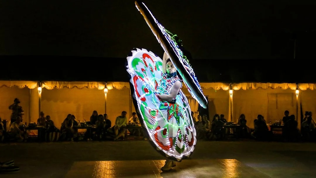 Desert safari performer in colorful illuminated costume during evening show.