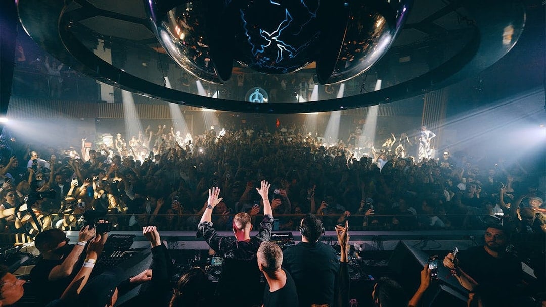 DJ performing at Camelphat event, Pacha Ibiza, with crowd dancing under club lights.