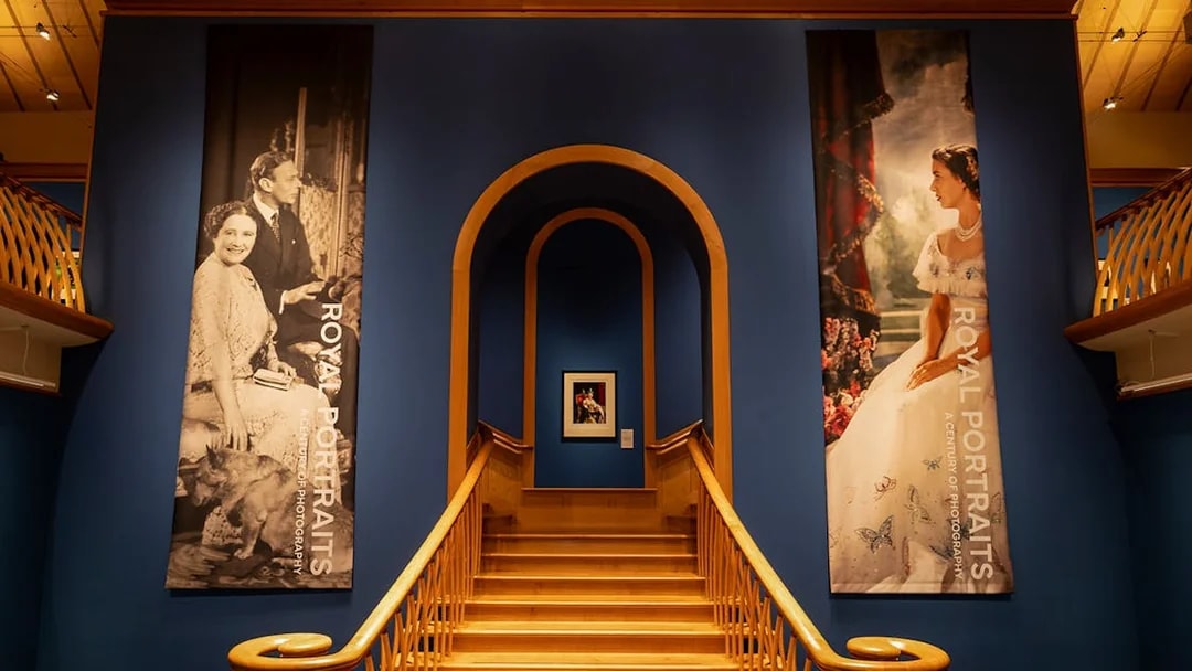 Staircase leading to The King's Gallery at the Palace of Holyroodhouse, featuring royal portraits.