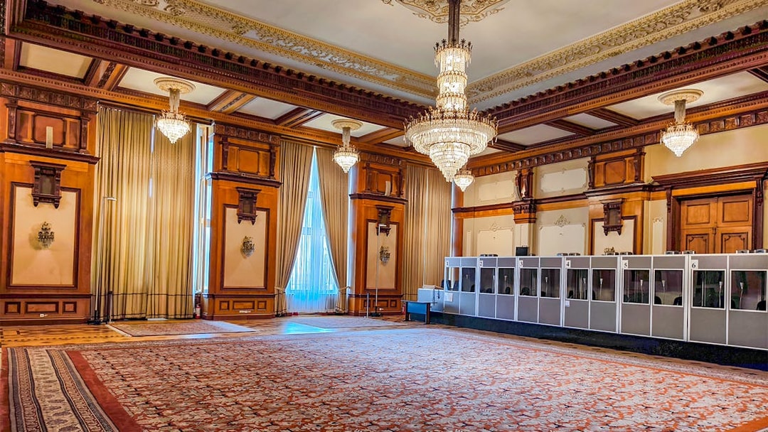 Palace of Parliament interior with ornate chandeliers and detailed wood paneling.