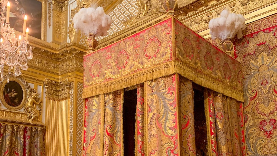 Versailles King's Apartment bedroom with ornate gold and red canopy bed.
