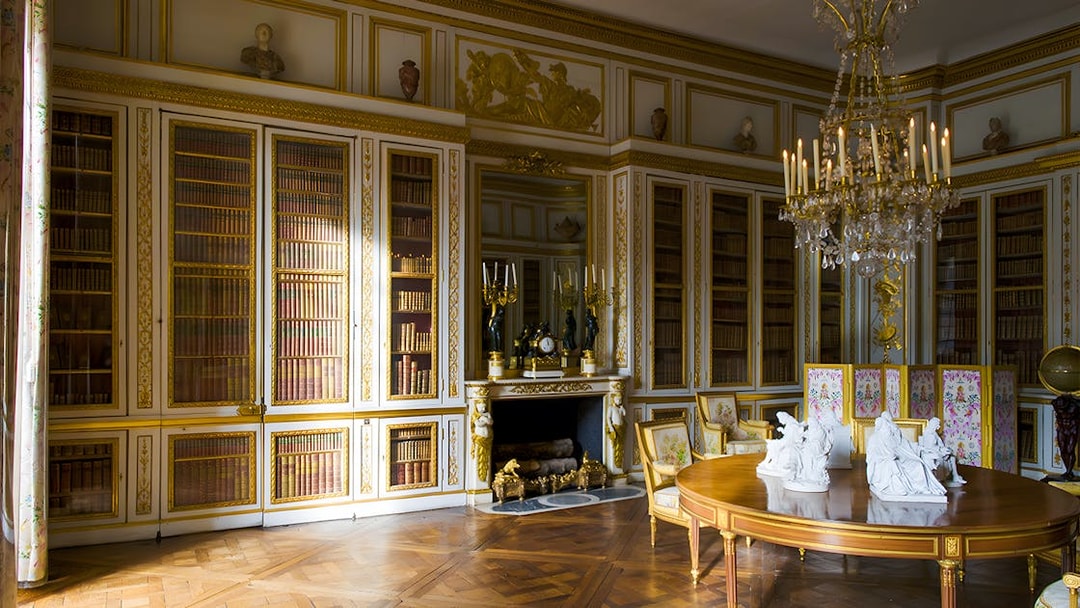 Louis XVI's Library in Versailles' King's Private Apartment with ornate bookshelves and chandelier.