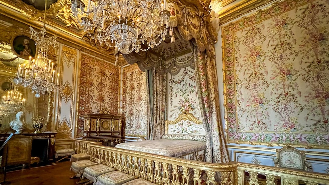 Queens apartment at Versailles Palace with ornate bed and chandelier.