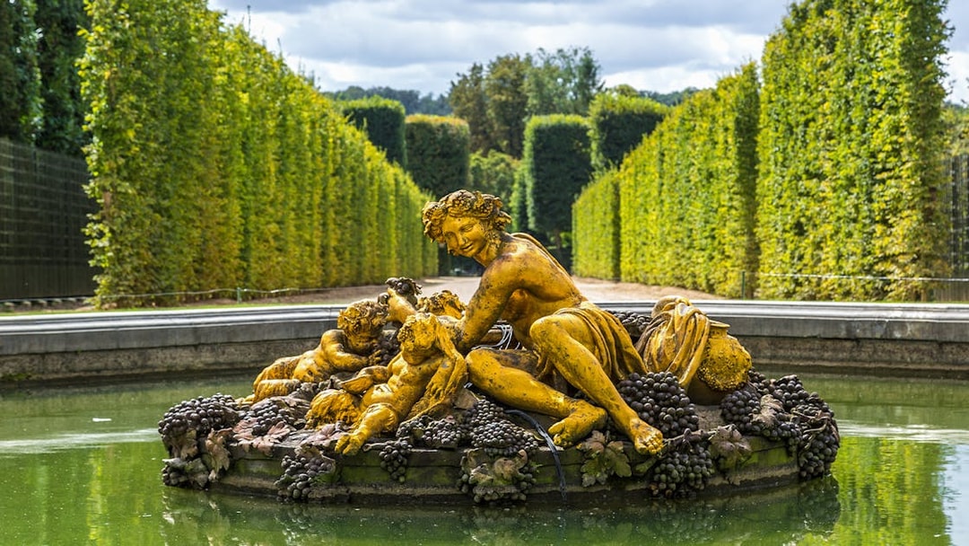 Fountain statue with figures and grapes in Versailles Palace gardens.