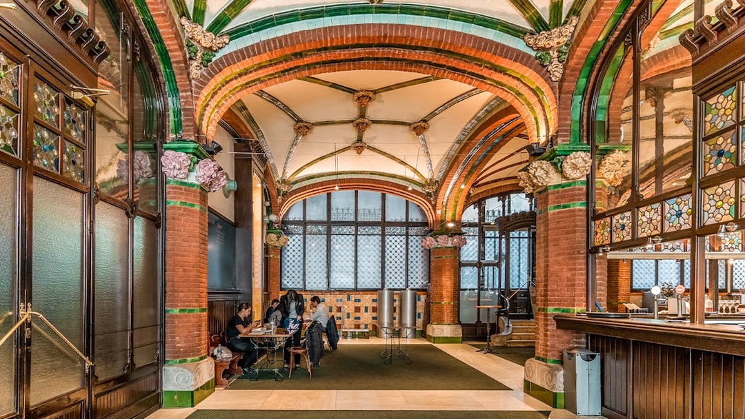 Hall inside Palau de la Musica Catalana with stained glass and ornate arches.