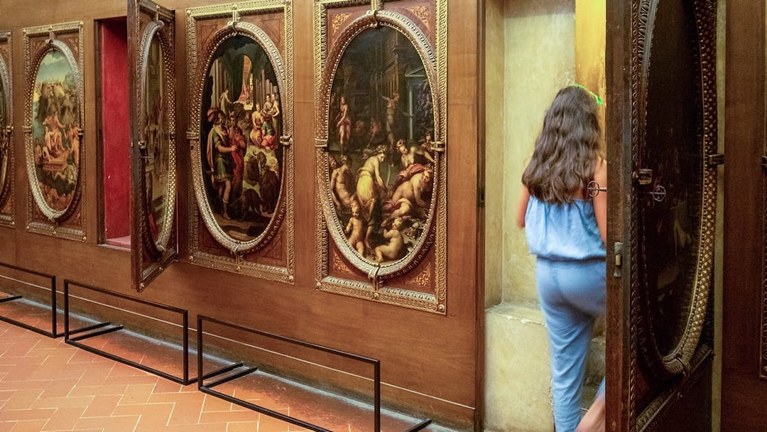 Palazzo Vecchio tour participant entering secret passage behind paintings.