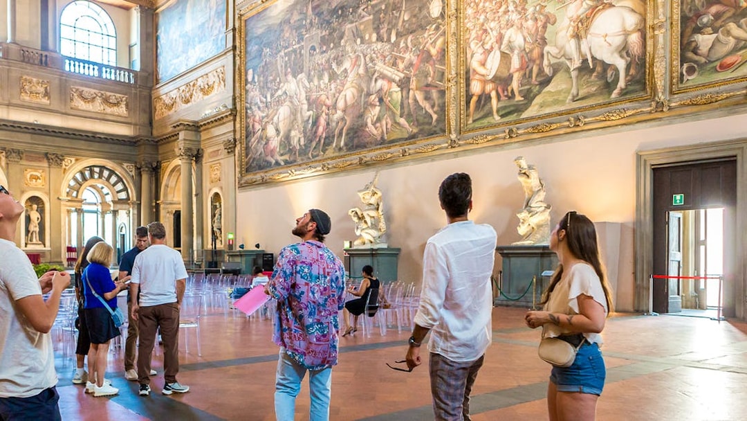 Visitors admiring artwork in Palazzo Vecchio museum, Florence, Italy.