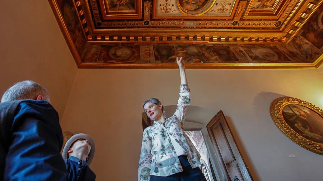 Guide explaining frescoes on the ceiling during Palazzo Vecchio Museum tour.