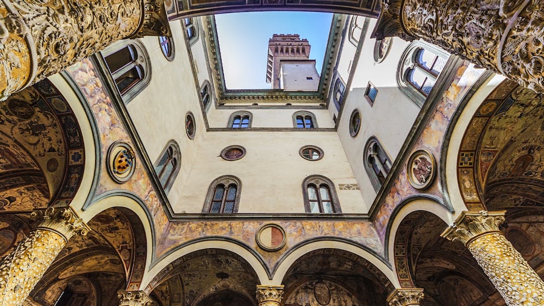 Palazzo Vecchio courtyard with ornate columns and tower view, Florence, Italy.