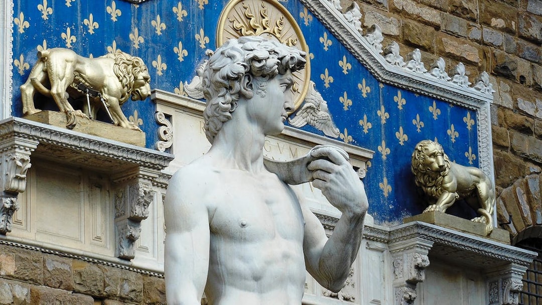 Statue of David at Palazzo Vecchio, Florence, with decorative lions in the background.