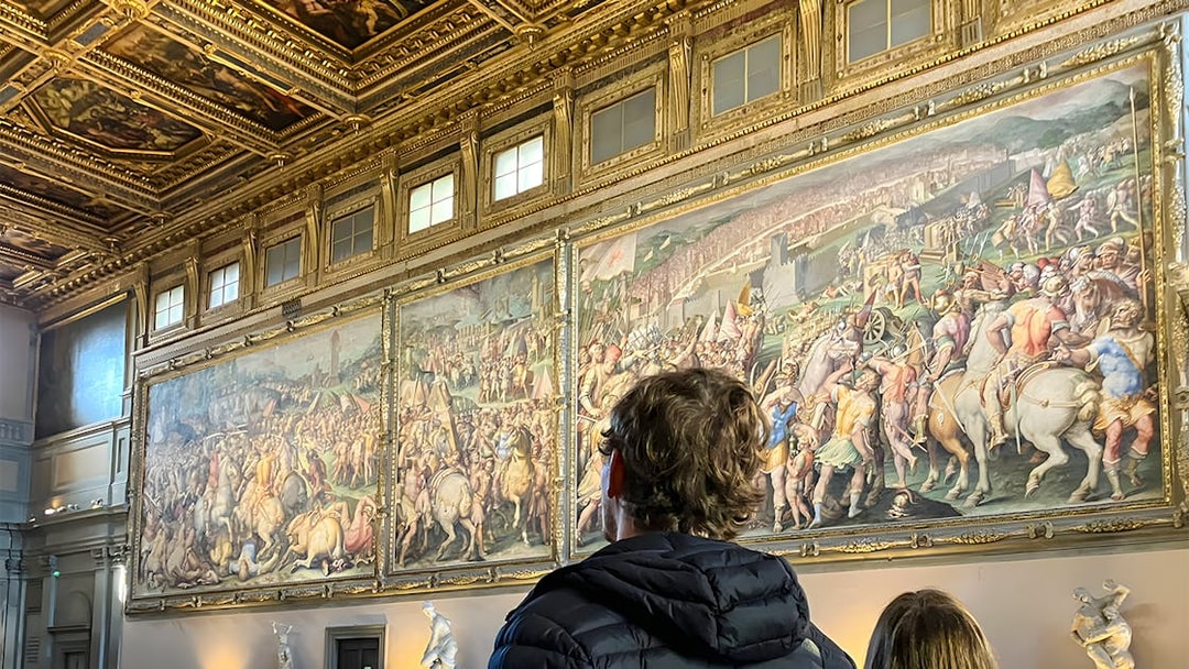 Tourists viewing frescoes inside Palazzo Vecchio, Florence.