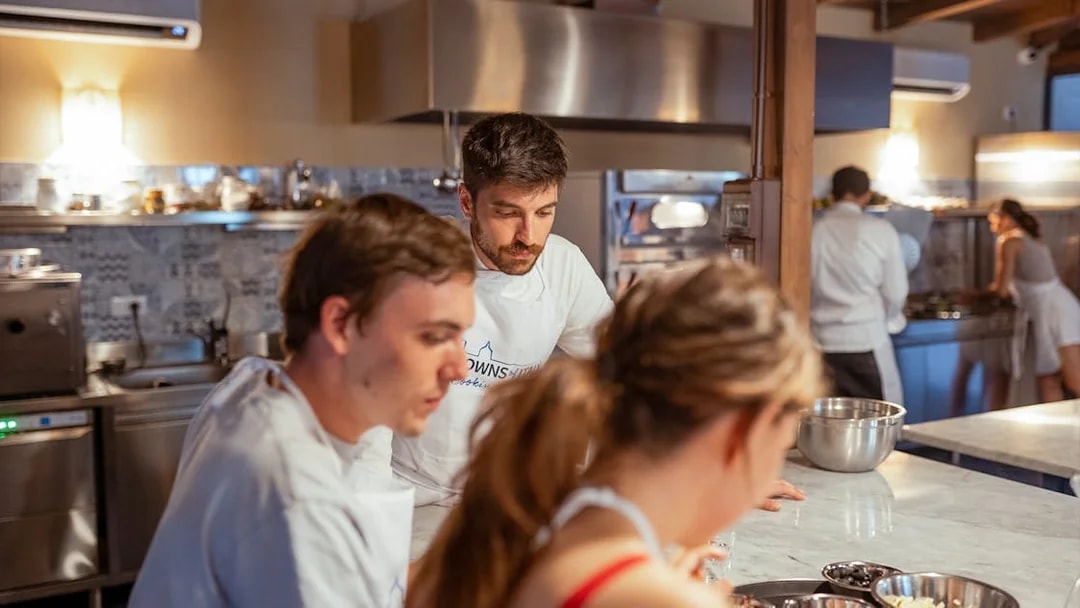 Cooking class participants preparing dishes in a Palermo kitchen.