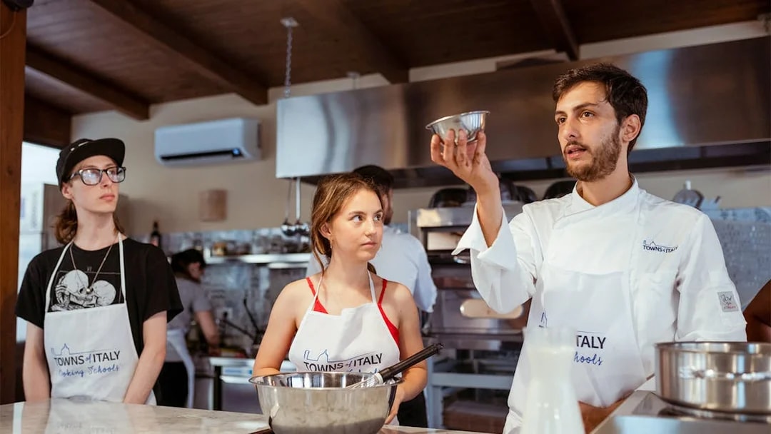 Cooking class participants learning from a chef in Palermo kitchen.