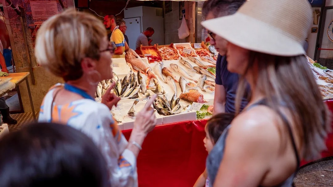 Market tour group exploring fresh seafood stall in Palermo.