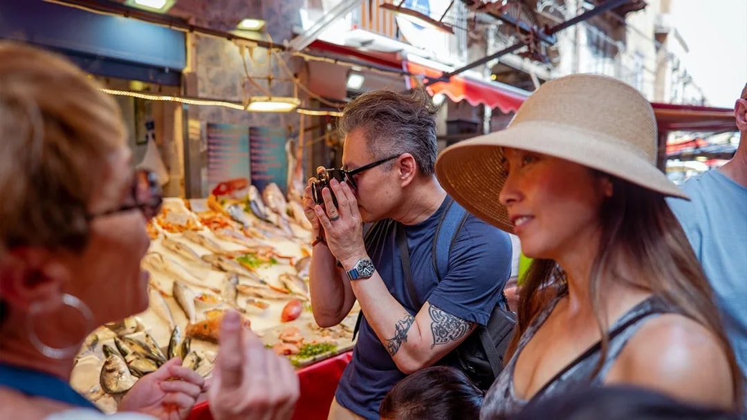 Tourists exploring a fish market during a cooking class in Palermo.