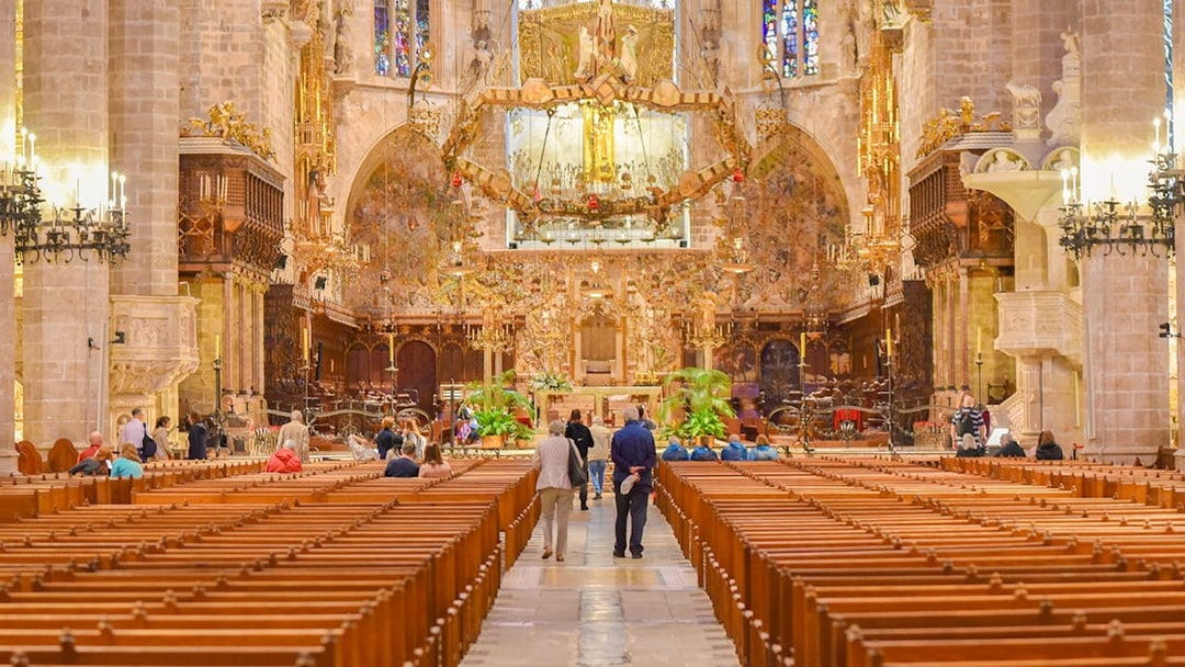 Palma Cathedral interior with ornate altar and stained glass windows.