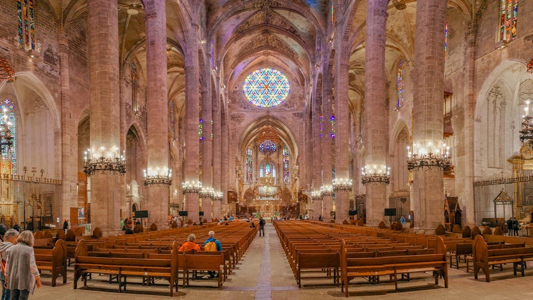 Palma Cathedral interior with stained glass windows and vaulted ceilings.