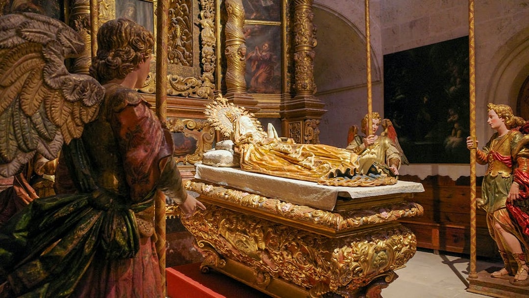 Religious statues in Palma Cathedral depicting angels around a golden altar.