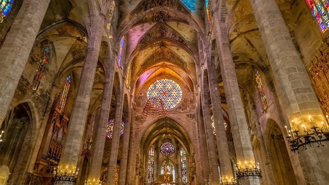 Gothic interior with stained glass windows and columns in Palma Cathedral.