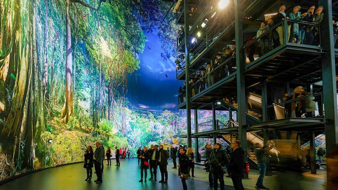 Visitors exploring panoramic rainforest exhibit at Panometer Dresden.