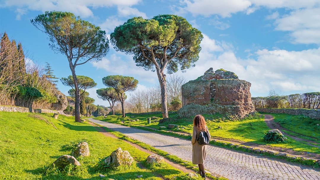 Walking along the Appian Way near ancient ruins and trees, Rome.