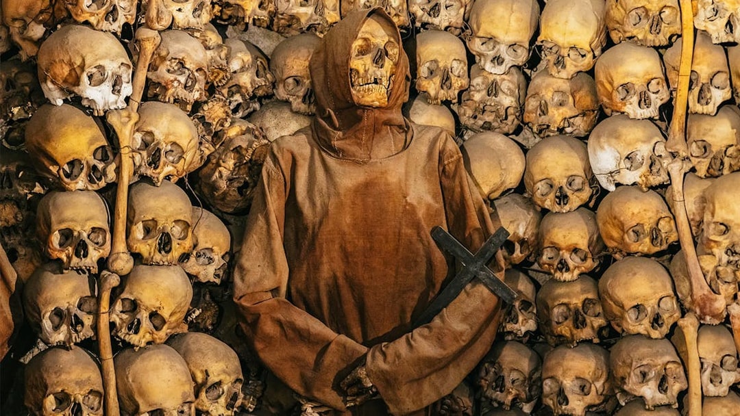 Skeleton in robe surrounded by skulls in Roman catacombs on the Appian Way.