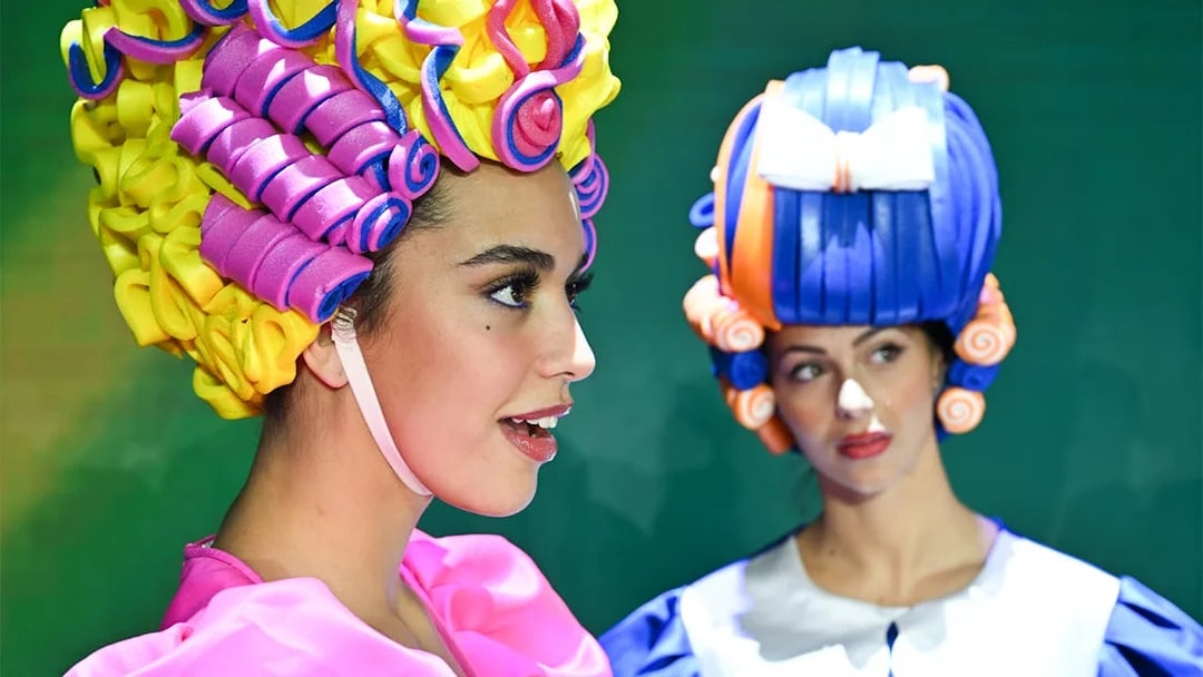 Performers in colorful wigs at Paris cabaret show.
