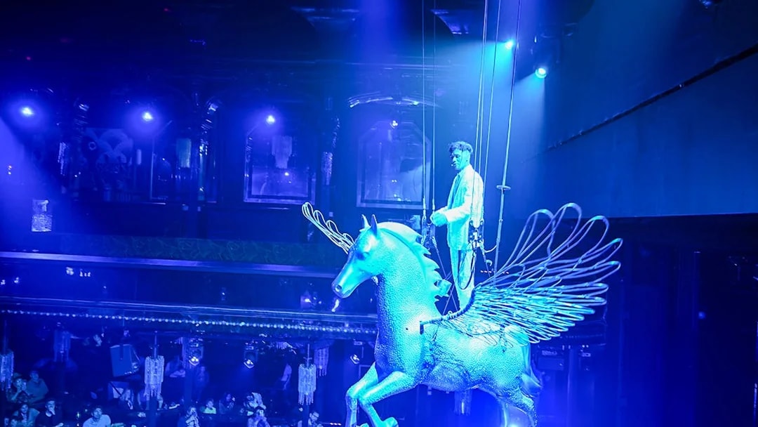 Performer on a winged horse at Paris cabaret show.