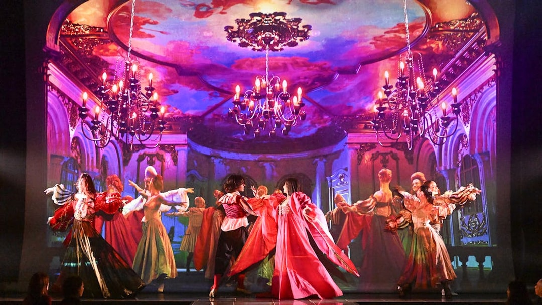Dancers in vibrant costumes perform on stage at a Paris cabaret with ornate backdrop.