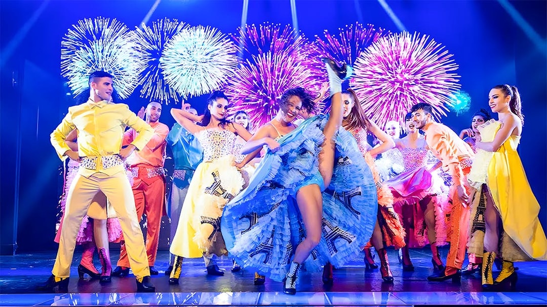 Dancers performing French Cancan at Paradis Latin in Cancun with fireworks in the background.