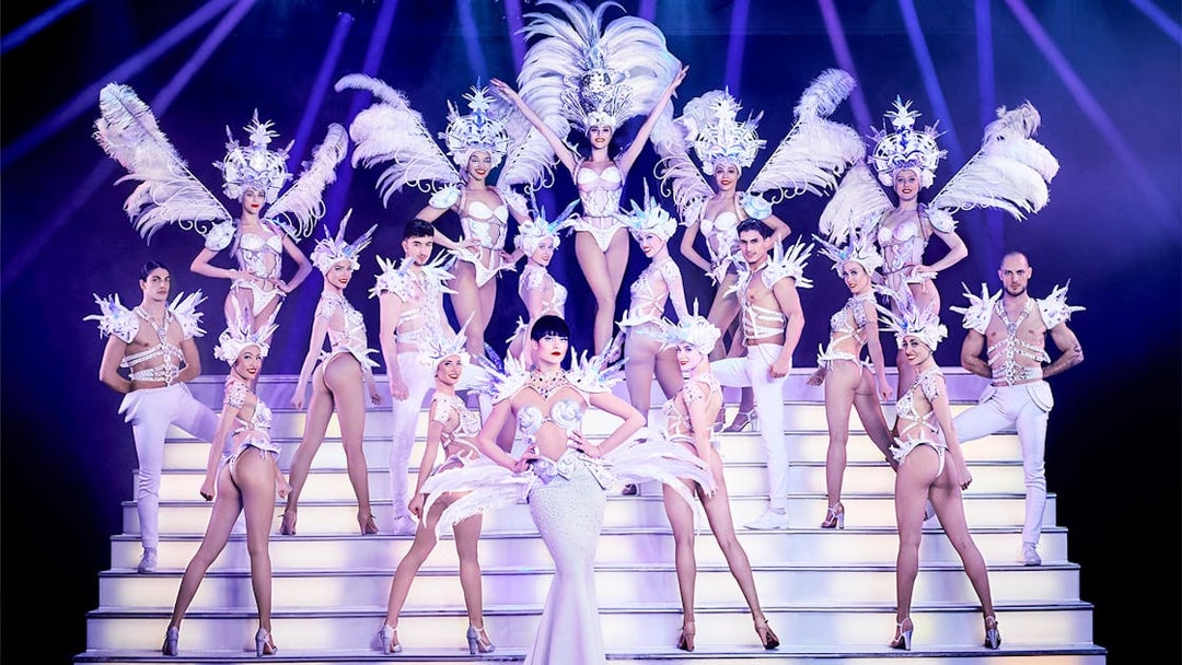 Performers in elaborate costumes on stage at Paradis Latin Christmas Eve show.