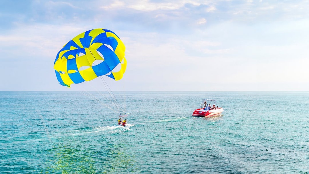 Parasailing over the ocean in Dubai with a colorful parachute and speedboat.