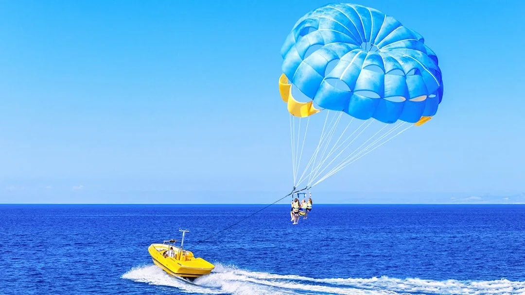 Parasailing over the ocean in Dubai with a yellow boat.